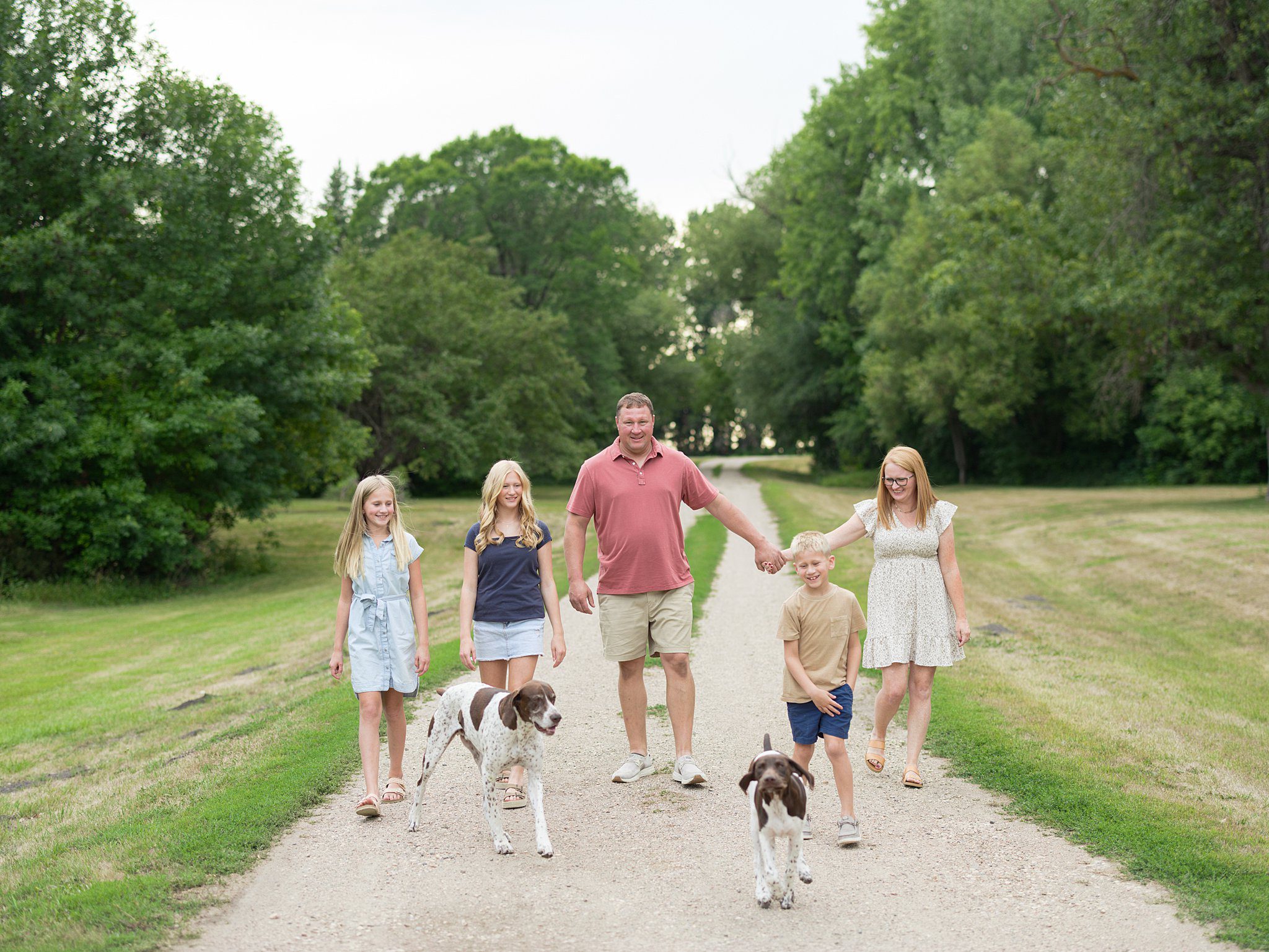Family of six walking together through grassy field during a summer family photography session in Grand Forks, North Dakota